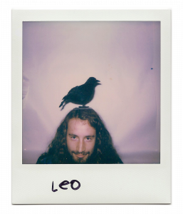 Leo, artist with only his face showing and a fake bird on his head