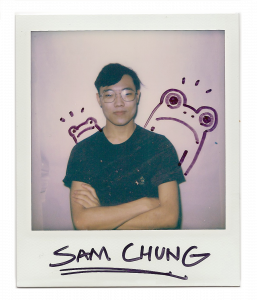 Sam, man standing confidently with sharpie drawn frogs behind him