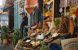 Preview of Dont forget Morrocco a man stanign next to a food stall